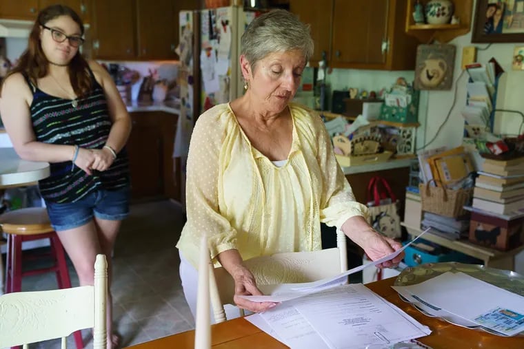 In her Gilbertsville, Pa., home, Susan Scott holds some of the "proof of life"  documents she needed to prove to Social Security she is actually alive, after the agency listed her as dead. In the background is her granddaughter, Taryn Scott.
