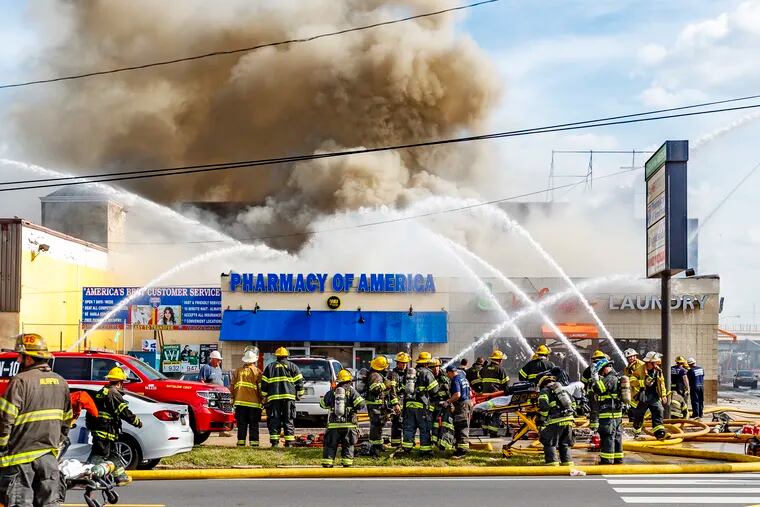 Heavy smoke pours out of the Pharmacy of America at Castor and Erie Avenues as Philadelphia firefighters battle to contain the blaze on Tuesday, June 25, 2019.