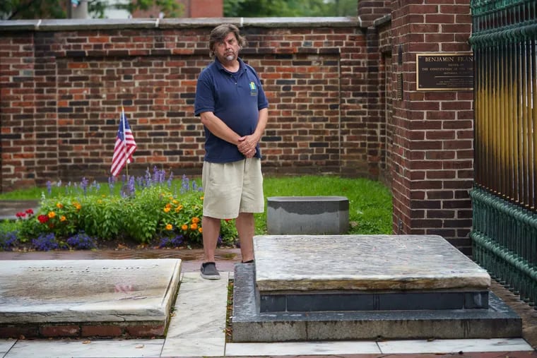 John Hopkins, Director of Operations Christ Church Preservation Trust, shown here next to the grave of Benjamin Franklin, right, in Philadelphia, July 8, 2019.