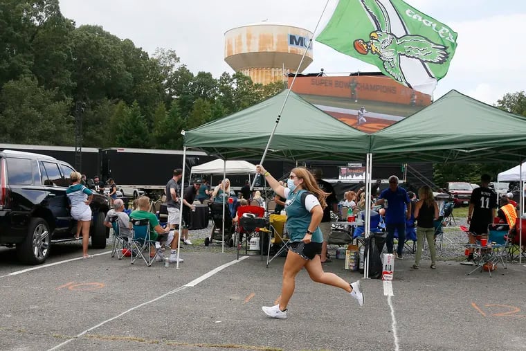 Eagles fan Erin Tinneny of Collegeville, Pa. runs with the Eagles flag after their first touchdown while watching the Philadelphia Eagles season opener at Innovative Catering Concepts in Williamstown. Hundreds of fans gathered for a tailgate in the South Jersey parking lot.