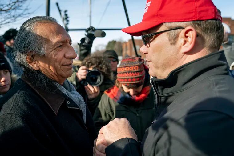 Guy Jones, left, and a supporter of President Donald Trump named Don join hands during a gathering of Native American supporters in front of the Catholic Diocese of Covington in Covington, Ky., Tuesday, Jan. 22, 2019. Jones organized Tuesday's gathering. (AP Photo/Bryan Woolston)
