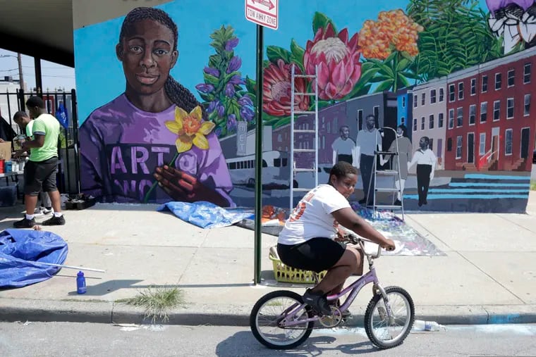 A boy rides his bicycle Monday, July 29. 2019 after volunteering to paint a mural outside the New Song Community Church in the Sandtown section of Baltimore. In the latest rhetorical shot at lawmakers of color, President Donald Trump over the weekend vilified  Rep. Elijah Cummings majority-black Baltimore district as a "disgusting, rat and rodent infested mess" where "no human being would want to live."