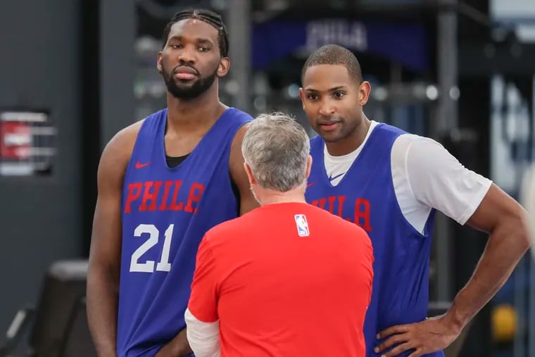 Joel Embiid (21) and Al Horford listening to coach Brett Brown at an October practice.