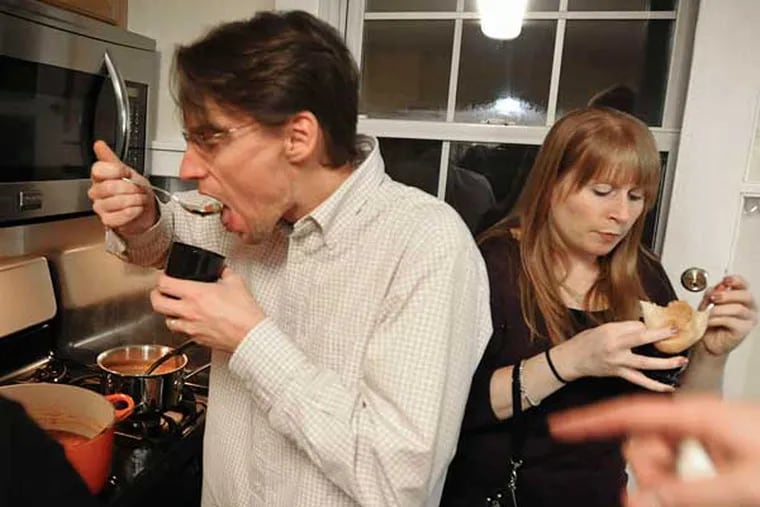Chris Roselle, Pam Daly sample soup at the "What a Crock" 10th-anniversary party at the home of Sara Goddard and Joe Daly. Goddard created a "best soup name" category, encouraging participants to get creative.  RON TARVER / Staff Photographer