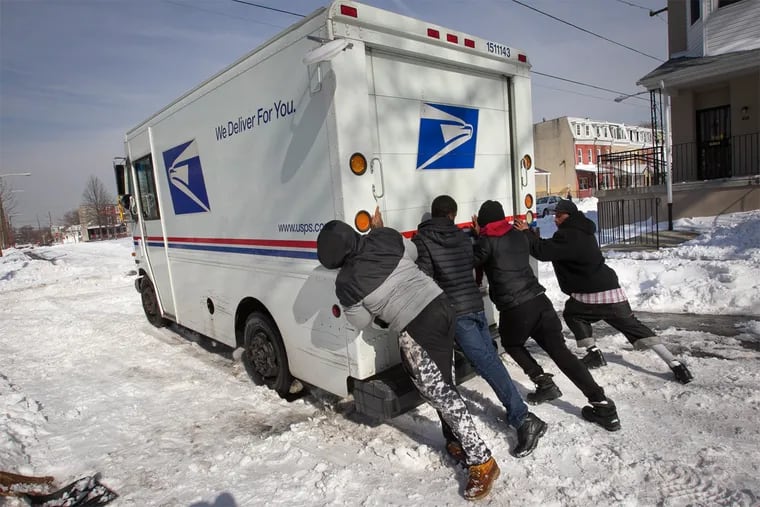 Young men from the Mantua section of Philadelphia attempt to help a stranded U.S Postal truck stuck in the snow and ice along Union St. at Fairmount on Monday afternoon.