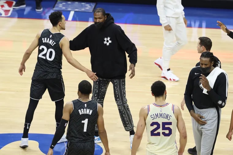 Kevin Durant (center) of the Nets greets Landry Shamet (left) and other teammates after their game against the Sixers Wednesday. Durant did not play in the game.