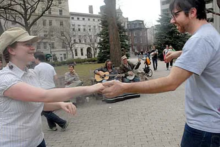 Erin Kroll and Dan Short dance in Rittenhouse Square while Jay Berkow
plays guitar and Sam Adams plays banjo on a nearby bench. (April Saul / Staff Photographer)