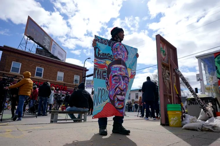 In this April 21 photo, a man holds a sign at George Floyd Square, in Minneapolis, a day after former Minneapolis police officer Derek Chauvin was convicted on all counts for the 2020 death of Floyd.