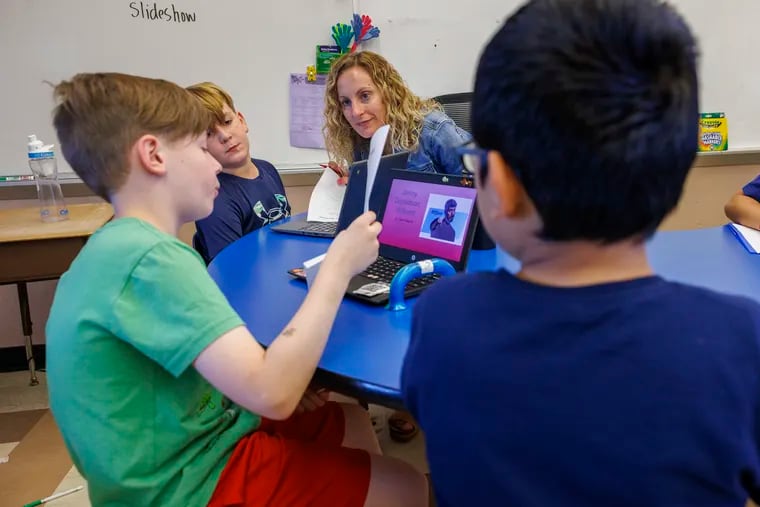 Third-grade teacher, Melissa Riedi, works with Owen Maguire, 9, pictured in green, on a Living Wax Museum lesson with a RIASEC component. Also shown are Wyatt Roeder, 9 and Hector Herrera, 9, (right).