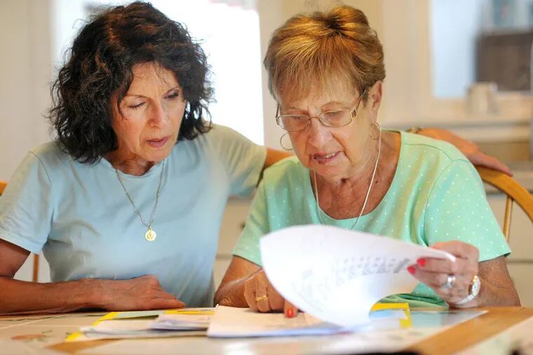 Donna Cliggett (left) helps her mother, Carmella DiBrino, as they look through paperwork after a scammer bilked her of $11,000 in gift cards in Hatboro, Pennsylvania.