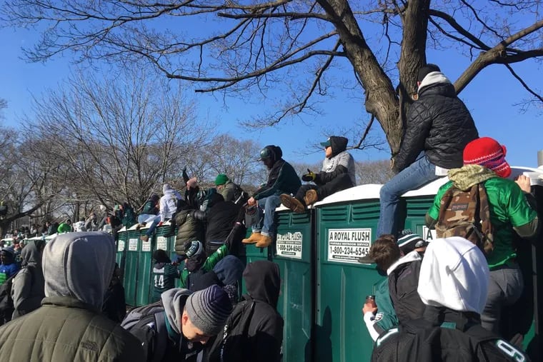 People climb on porta-potties to view the parade. In one area, a row of porta potties caved in beneath the weight of fans.
