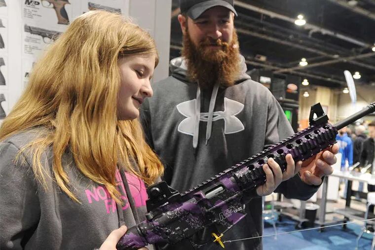 A girl and her father examine a rifle at the Outdoor Show in Harrisburg last winter.