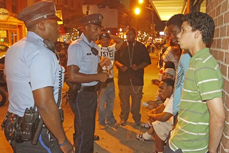 Philadelphia Police Officers Brandy McMillan (left) and Jamarr Leary question youths at Third and South after 9 p.m., the curfew deadline. (Akira Suwa / Staff Photographer)