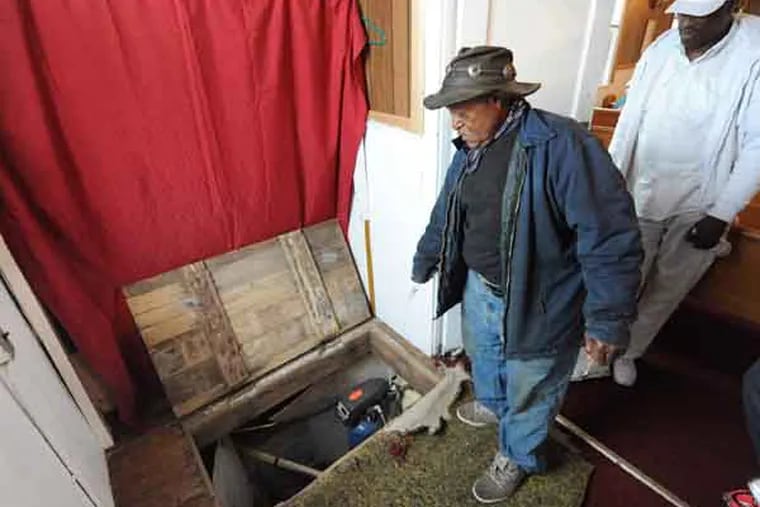 Bill Streater (left) and Greg Carter , members of Mount Zion A.M.E., peer through a trapdoor into a crawl space where runaway slaves would hide. The church was a stop on the Underground Railroad. (CLEM MURRAY / Staff Photographer)