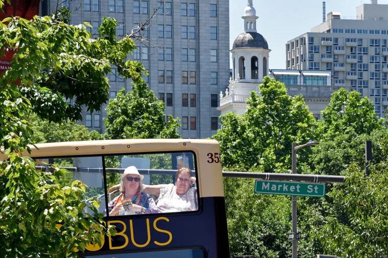 Tourists ride in the exposed upper level of a double-decker bus near Independence Mall on June 9, a pleasant day ahead of the heat wave now gripping the region.