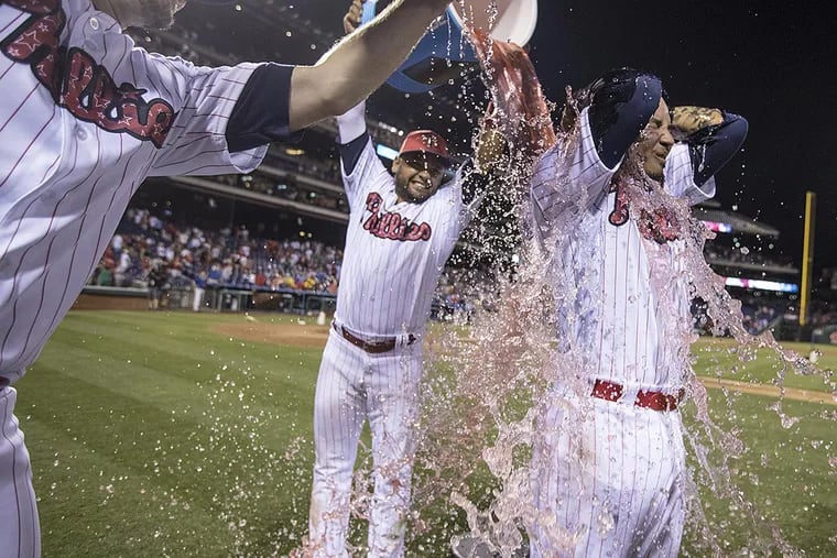 Freddy Galvis (right) has water coolers dumped on him by Tommy Joseph (left) and Anres Blanco (center) after the Phillies defeated the Pirates, 4-0.