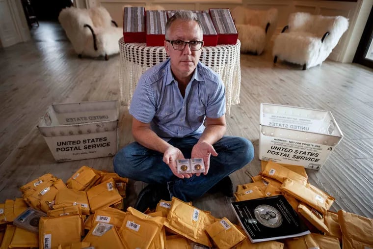 Dwight Manley, 54, holds two of his favorite coins from the Baker Collection, the Perkins Private Pattern and the Washington D.C. Emancipation Tag, inside his home in Brea, Calif. Manley, surrounded by mailers containing the Baker trove, anonymously acquired almost the entire collection of coins and medals sold at auction by the Historical Society of Pennsylvania in November.