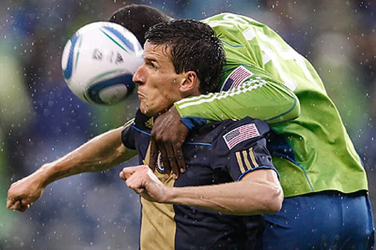 Sounders' John Kennedy Hurtado lands on the Union's Sebastien Le Toux, left, as he tries to head the ball. (David Maialetti / Staff Photographer)