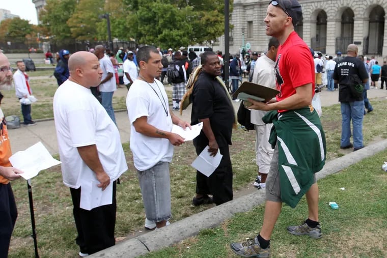 Adam Bruckner of Philly Restart explains the proper protocol for receiving a check on Vine Street between 18th and 19th Street in Center City on Monday, September 29, 2014. The checks help people get ID's necessary to get into shelters, half-way house and possibly finding a job.