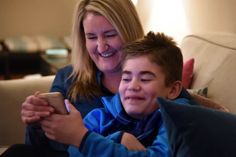 Marisa DiChiacchio looks at a video on her phone with her son Connor Dobbyn, 11, at their Chester County home Jan. 13, 2020. Connor has Sanfilippo syndrome - so-called Childhood Alzheimer's - a genetic condition so rare that it afflicts only 1 in 1 million children.