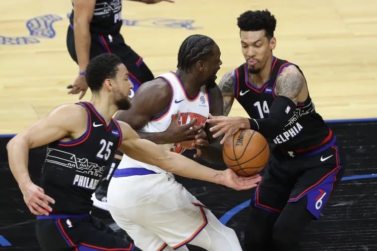 Ben Simmons, left, and Danny Green, right, of the SIxers strip the ball away from Julius Randle of the Knicks during the 1st half of a NBA game at the Wells Fargo Center on March 16, 2021.