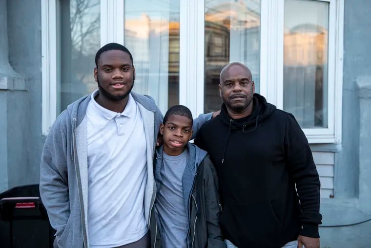 Vaughn Jackson, 52, legal guardian to Zaveonte Winn, 17, and Xavier Winn, 14, pose for a portrait at their home in Philadelphia in December.