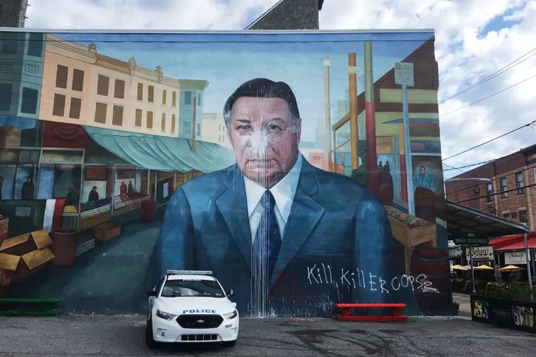 A police car is parked in front of the Frank Rizzo mural after it was vandalized in South Philadelphia in August.