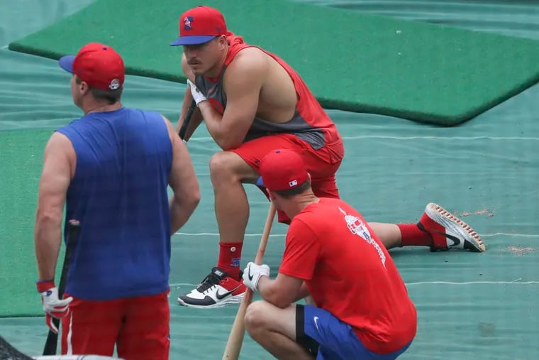 Phillies catcher J.T. Realmuto (center) kneels during practice at Citizens Bank Park on Wednesday.
