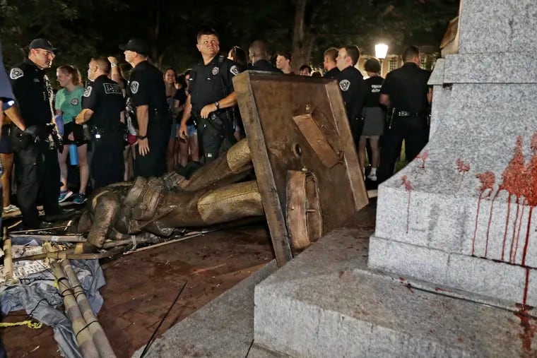 FILE - In this Aug. 20, 2018, file photo, police stand guard after the confederate statue known as Silent Sam was toppled by protesters on campus at the University of North Carolina in Chapel Hill, N.C. Leaders of North Carolina’s flagship university are meeting to decide the fate of a Confederate monument torn down by protesters. The chancellor and trustees of the University of North Carolina at Chapel Hill were finalizing a plan Monday, Dec. 3, for the century-old bronze statue known as “Silent Sam.” (AP Photo/Gerry Broome, File)