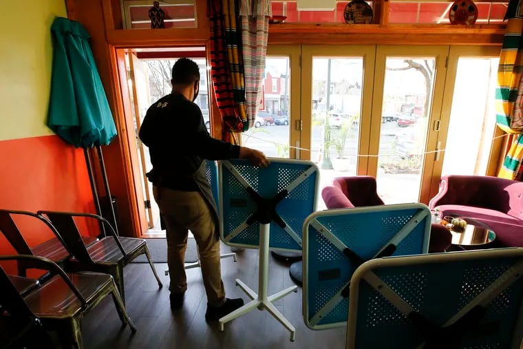 Eyob Moges prepares to set tables and chairs outside the Buna Cafe along the 5100 block of Baltimore Avenue in West Philadelphia on Thursday, Nov. 19, 2020. The restaurant is new and opened during the pandemic.
