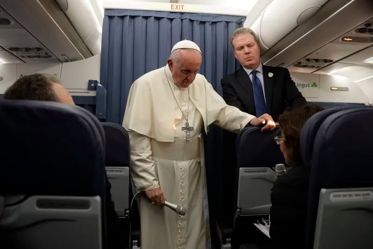 Pope Francis, flanked by Vatican spokesperson Greg Burke, listens to a journalist's question during a press conference aboard of the flight to Rome at the end of his two-day visit to Ireland, Sunday, Aug. 26, 2018.