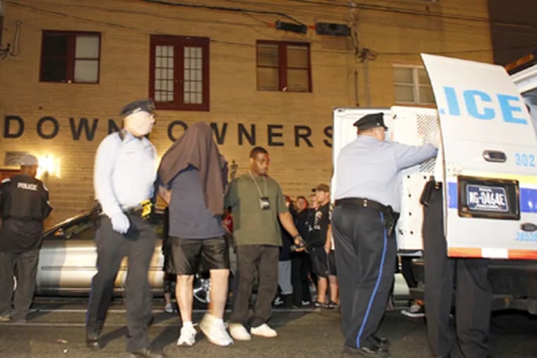 Police escort a man from the Downtowners clubhouse after the raid. Arrested were 13 people, including 10 women and two executives of the Fancy Brigade. (Yong Kim / Staff Photographer)