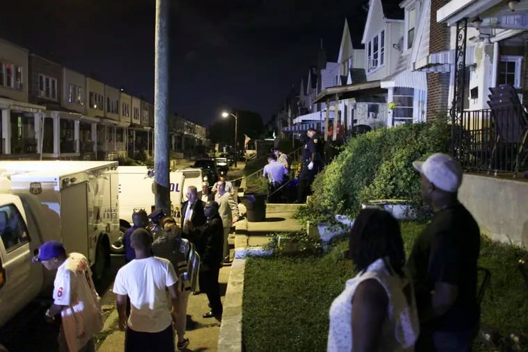 Family members watch as police remove a body from a home on Vista Street near Torresdale Avenue in the Holmesburg section of Philadelphia on Saturday Aug. 24, 2014, after two women were found shot to death. According to police the women were found just after 5:30 p.m. in two different parts of the house.  For the Daily News/ Joseph Kaczmarek