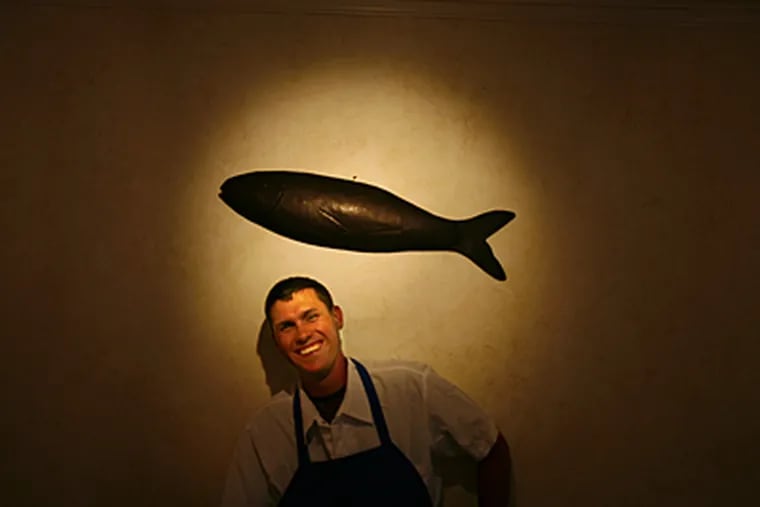 Chip Roman, chef and owner, under a black fish on the wall in the dining room at Blackfish in Avalon. (Eric Mencher  / Inquirer)