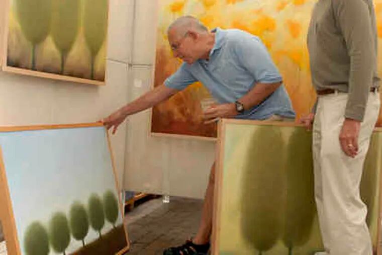 Ken Baron (left) looks over David Gordon's work at the Rittenhouse Square Fine Art Show. Baron, who lives in Washington Square, acquired three other Gordon paintings at past art shows.