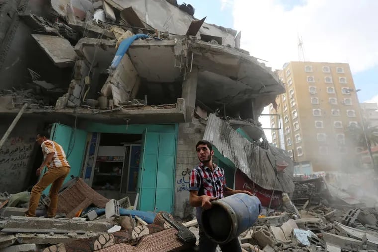 A Palestinian salvages a gas cylinder from the rubble of an apartment building hit by an Israeli missile strike in Gaza City. Israeli troops pushed deeper into Gaza on Friday in an offensive to weaken the Islamist militant group Hamas.