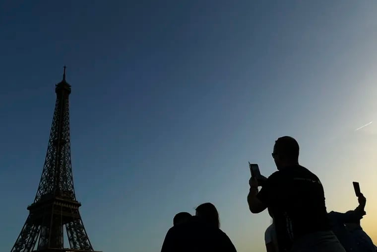 People are silhouetted as they photograph the Eiffel Tower in Paris.