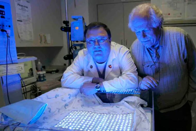 Neonatologist Harel Rosen (left) and his father, engineer Arye Rosen, show a prototype of their solar-powered blanket that treats jaundice with light therapy. It has 200 blue LED lights embedded in it, and can be especially useful for areas that lack electricity.