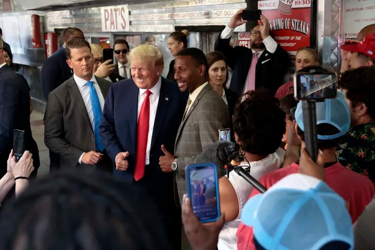 Former President Donald Trump takes a photo with Darwin Cooper of Vineland, N.J., during his visit to Pat’s King of Steaks in South Philadelphia Friday night.