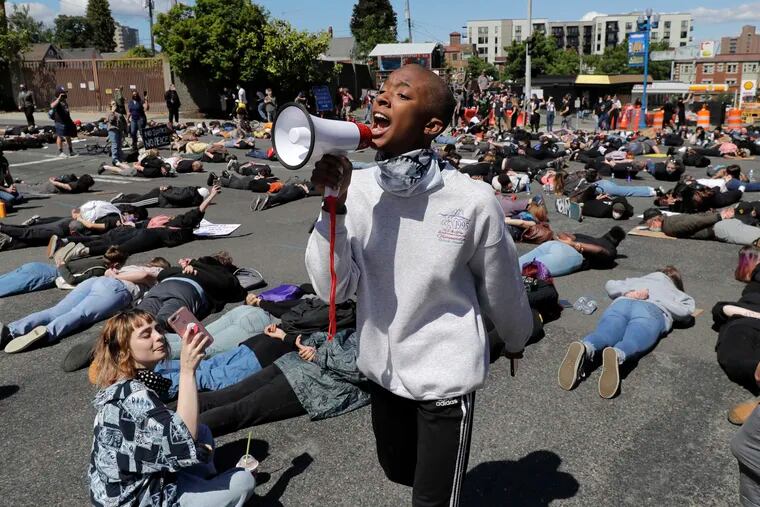 A person leads chats with a megaphone as others block traffic as they lie face-down on the street at an intersection in Tacoma, Wash., for 8 minutes and 46 seconds during a protest Monday, June 1, 2020, against police brutality and the death of George Floyd, a black man who died after being restrained by Minneapolis police officers on May 25.