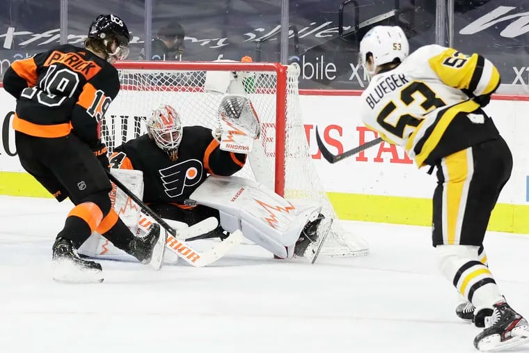 Flyers goaltender Alex Lyon saves the puck with teammate center Nolan Patrick against Penguins center Teddy Blueger.