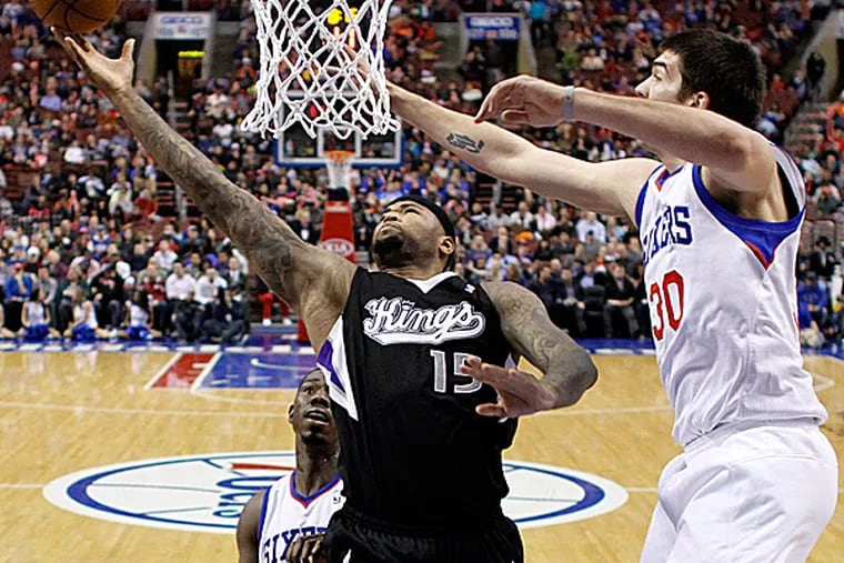 The Kings' DeMarcus Cousins goes up to shoot between the 76ers' Henry Sims and Byron Mullens during the first half. (Matt Slocum/AP)