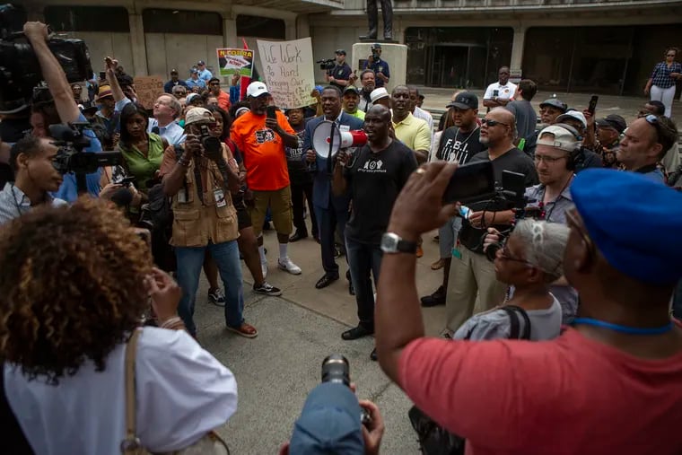 Solomon Jones speaks through a megaphone as a crowd gathers outside Philadelphia Police Headquarters at Eighth and Race Streets on Friday to protest the 330 active Philadelphia police officers included in a database of racist or otherwise offensive Facebook comments.
