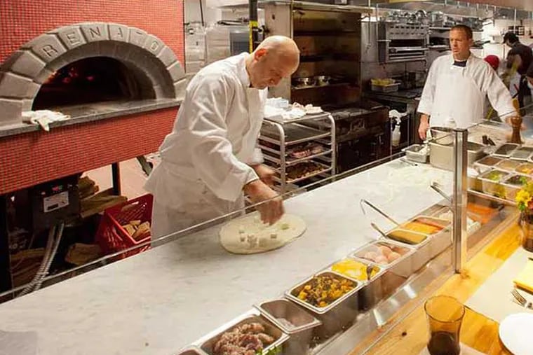 Chef Marc Vetri (left) works the pizza station in the kitchen of his new Osteria location at Moorestown Mall.