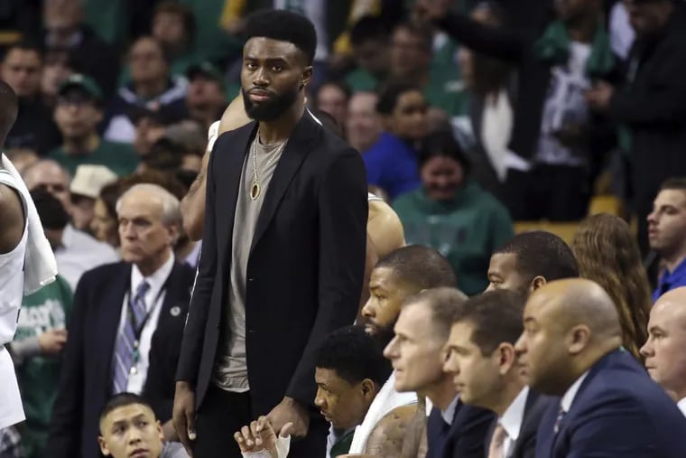 Jaylen Brown stands next to the Celtics bench in his street clothes during Boston’s Game 1 win over the Sixers on Monday.