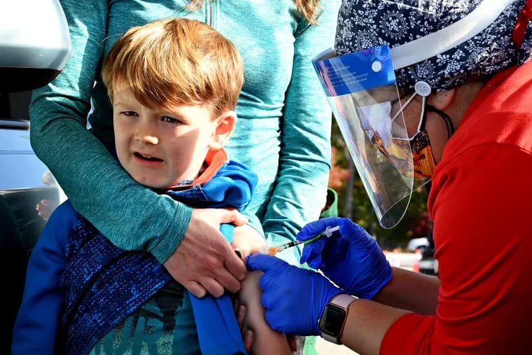 Amanda Moon of Haddonfield holds her son Lucas, 6, as Cooper University Health Care nurse educator Christina Polizzi (right) administers his shot at the Camden County drive-thru pediatric COVID-19 vaccine clinic.