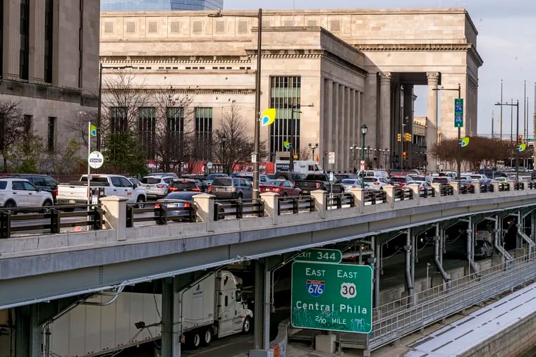 Local traffic moves on Schuylkill Ave. near the William H. Gray III 30th Street Station (rear) as  more vehicles travel on the interstate I-76 Schuylkill Expressway underneath on Jan. 23, 2024.