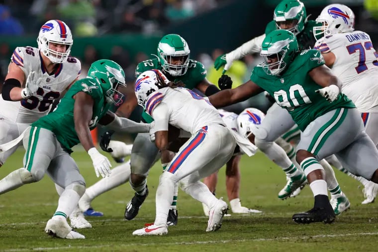 Eagles defensive tackle Jordan Davis (right), and linebacker’s Zach Cunningham (center) and Nicholas Morrow rally to make a tackle on Sunday.