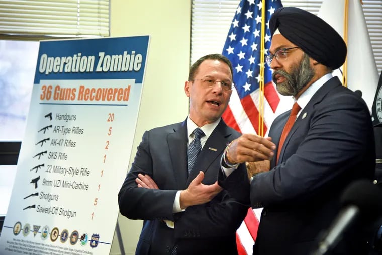 Pennsylvania Attorney General Josh Shapiro (left) and New Jersey Attorney General Gurbir S. Grewal confer after a news conference in Camden at which they announced that 36 guns were recovered and five people charged as part of a major gun-trafficking case called Operation Zombie. They were joined by a dozen local, state, and federal law enforcement partners.
