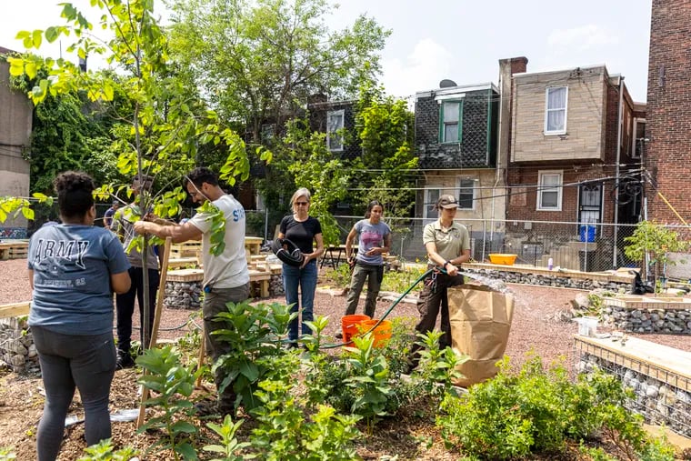 Carmelita Rosner, community engagement specialist, watering plants as volunteers and organizers are working on the park in Southwest Philadelphia Saturday.